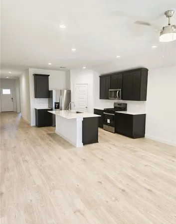 a large white kitchen with kitchen island granite countertop a stove top oven a sink a dining table and chairs