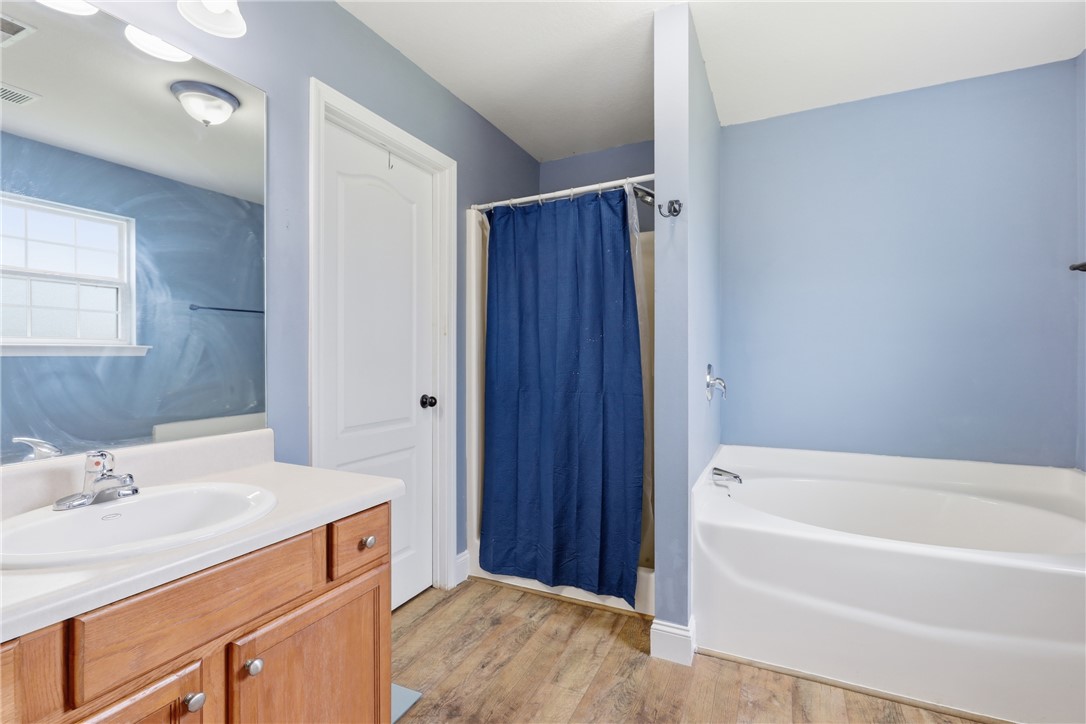 105 Lacy Lane Anderson, SC 29621 - Photo 10 of 16 A clean, bright bathroom features a single vanity, a shower with a privacy curtain, and a relaxing soaking tub.