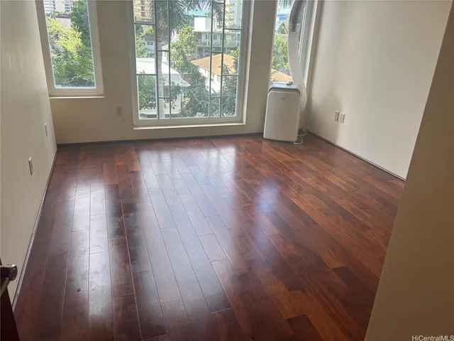 a view of an empty room with wooden floor and a window