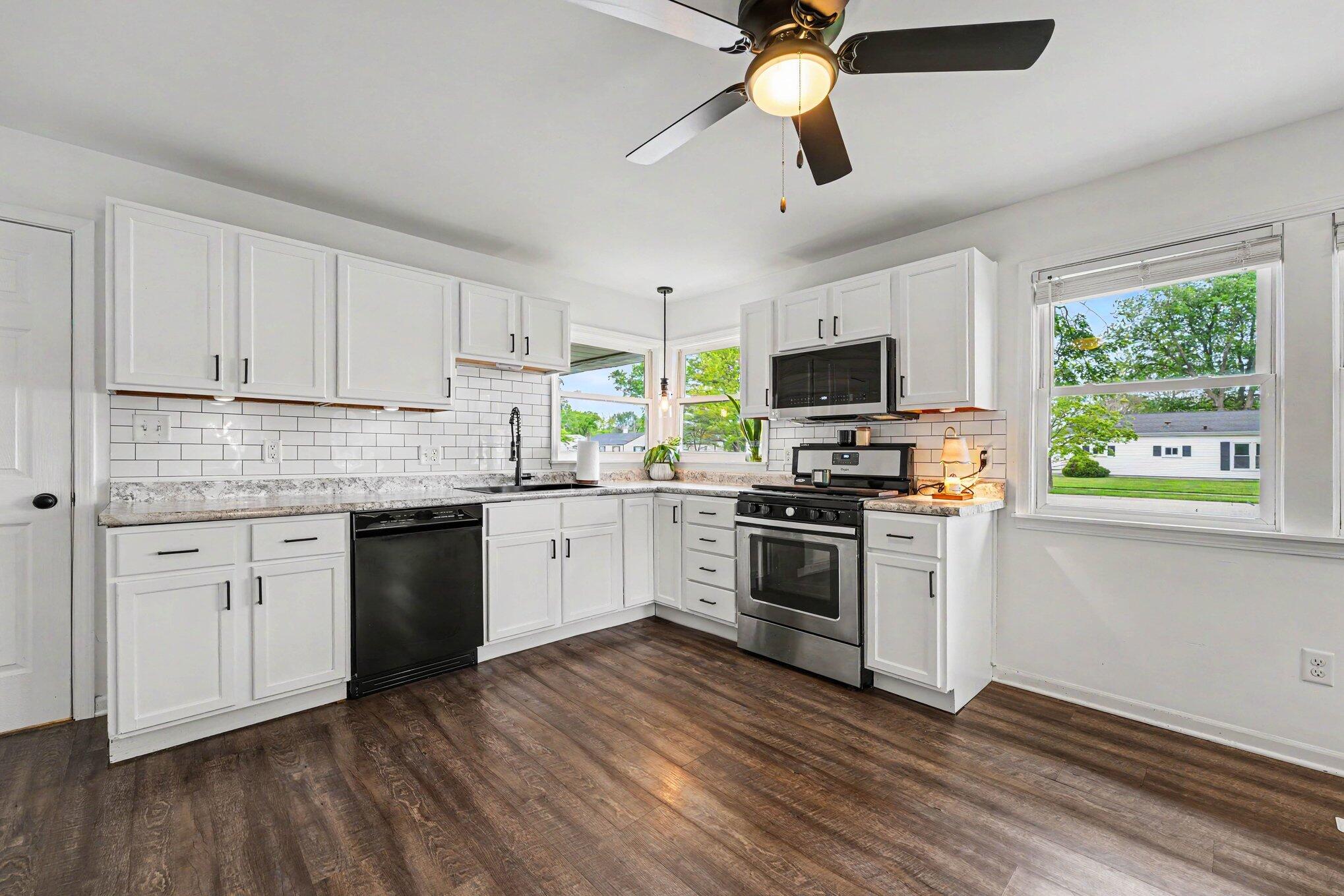 835 North Indiana Street Griffith, IN 46319 - Photo 6 of 19 a kitchen with granite countertop a stove top oven a sink dishwasher a dining table and chairs with wooden floor