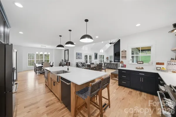a large kitchen with stainless steel appliances a stove a sink a dining table and chairs with wooden floor