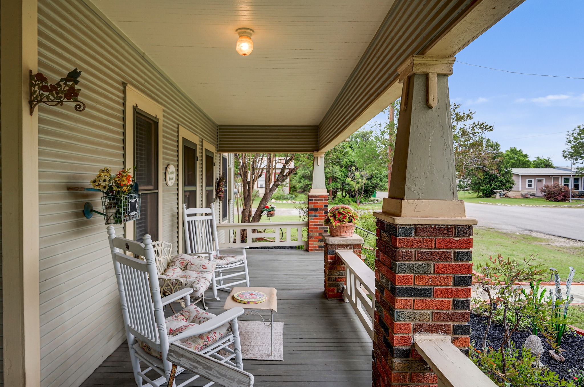 719 Elm Street Blanco, TX 78606 - Photo 5 of 25 Inviting front porch featuring a wood-finish floor, detailed brick pillars, and horizontal siding