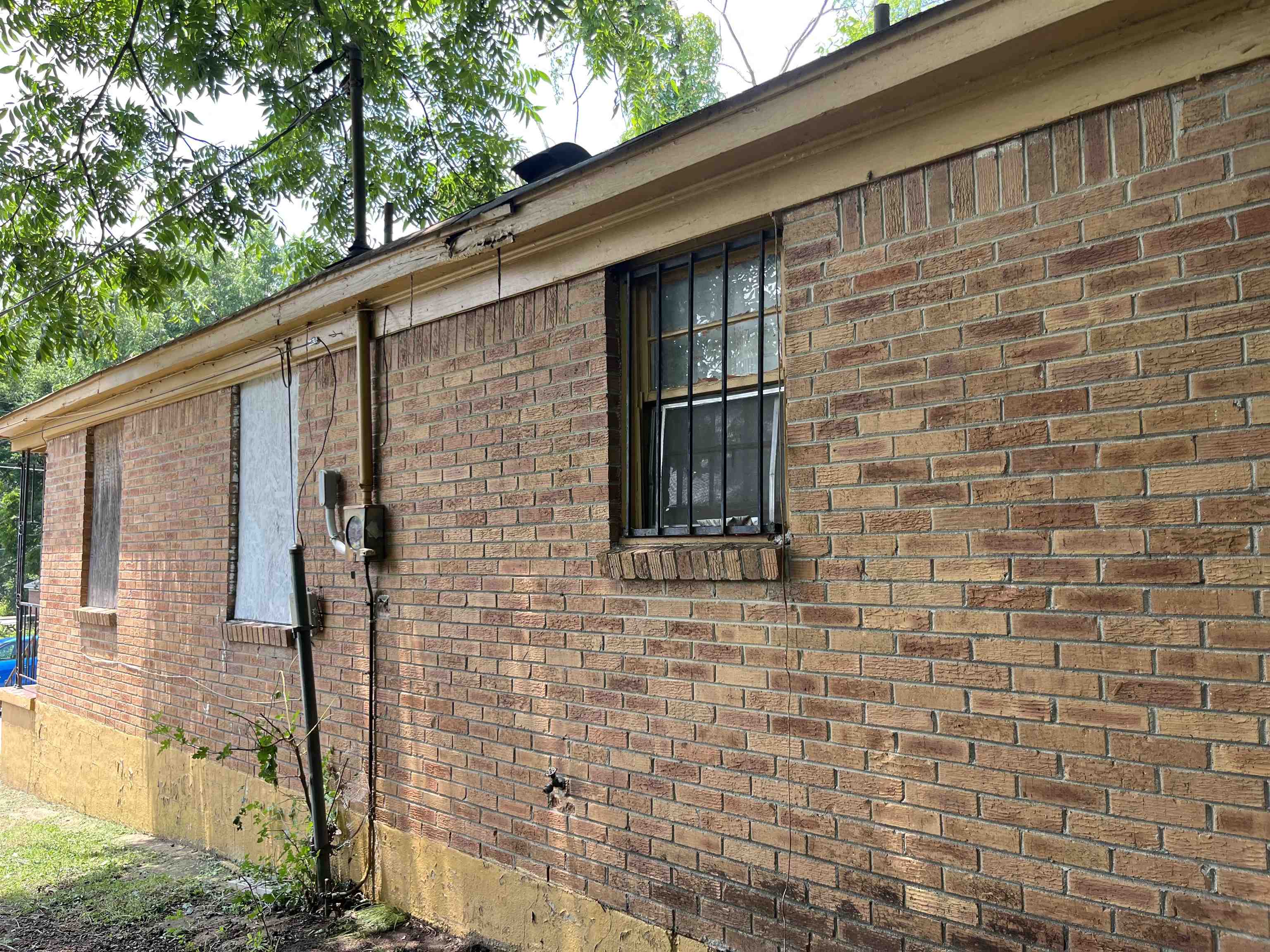 100 Silverage Avenue Memphis, TN 38109 - Photo 3 of 30 Brick exterior featuring a painted foundation, single-pane windows, and a partially boarded window