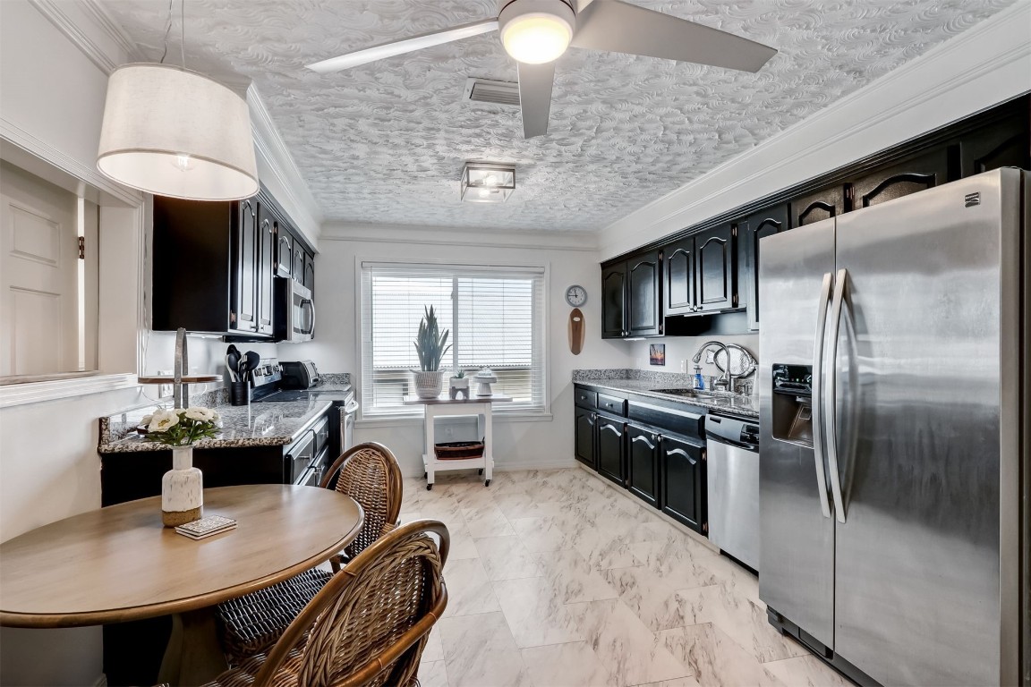 338 Tarpon Avenue Fernandina Beach, FL 32034 - Photo 12 of 36 a kitchen with kitchen island granite countertop a sink stainless steel appliances cabinets and a counter top space