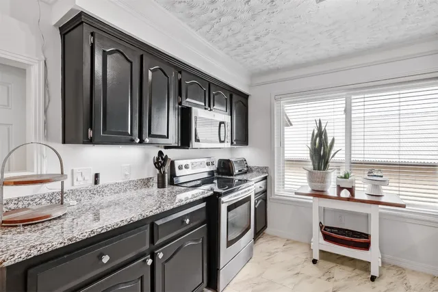 a kitchen with granite countertop stainless steel appliances a sink and refrigerator