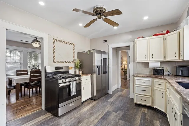 a kitchen with stainless steel appliances a stove a sink dishwasher a refrigerator and white cabinets with wooden floor