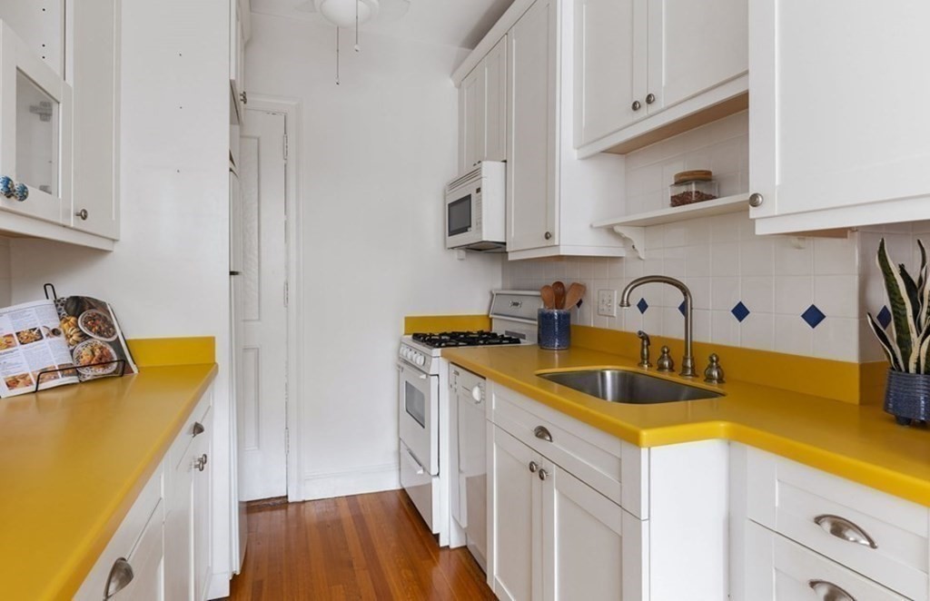 5 Arlington Street, Unit 34 Cambridge, MA 02140 - Photo 6 of 12 a kitchen with stainless steel appliances granite countertop a sink stove and white cabinets with wooden floor