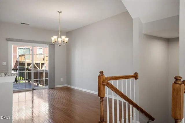 a view of a hallway with wooden floor and chandelier