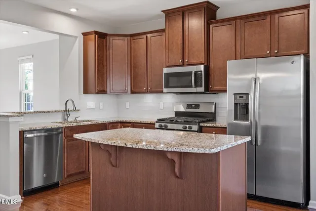 a kitchen with stainless steel appliances granite countertop a refrigerator stove microwave sink and cabinets
