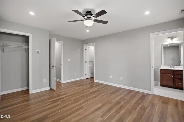 an empty room with wooden floor and a ceiling fan