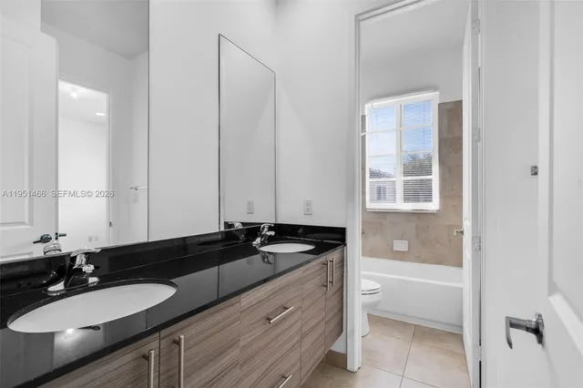 a bathroom with a granite countertop sink and a bathtub