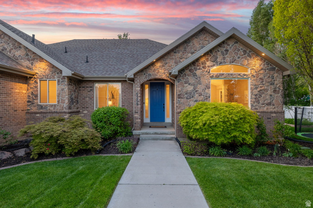 6208 West Bull River Road Highland, UT 84003 - Photo 70 of 90 Stone and brick exterior featuring a prominent blue entry door, gabled rooflines, and a concrete pathway