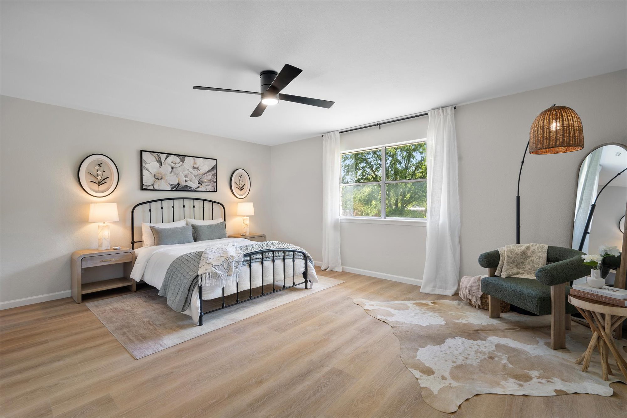 109 Woodland Road Georgetown, TX 78628 - Photo 22 of 40 Natural light bathes this spacious primary bedroom, featuring light wood-look flooring and a modern ceiling fan.