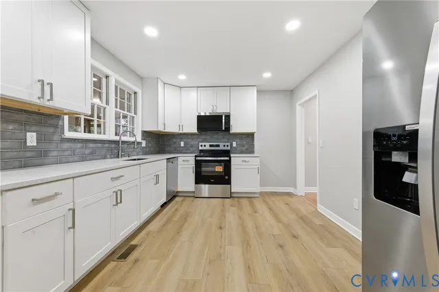 a large kitchen with granite countertop a stove top oven a sink dishwasher and a refrigerator with wooden floor