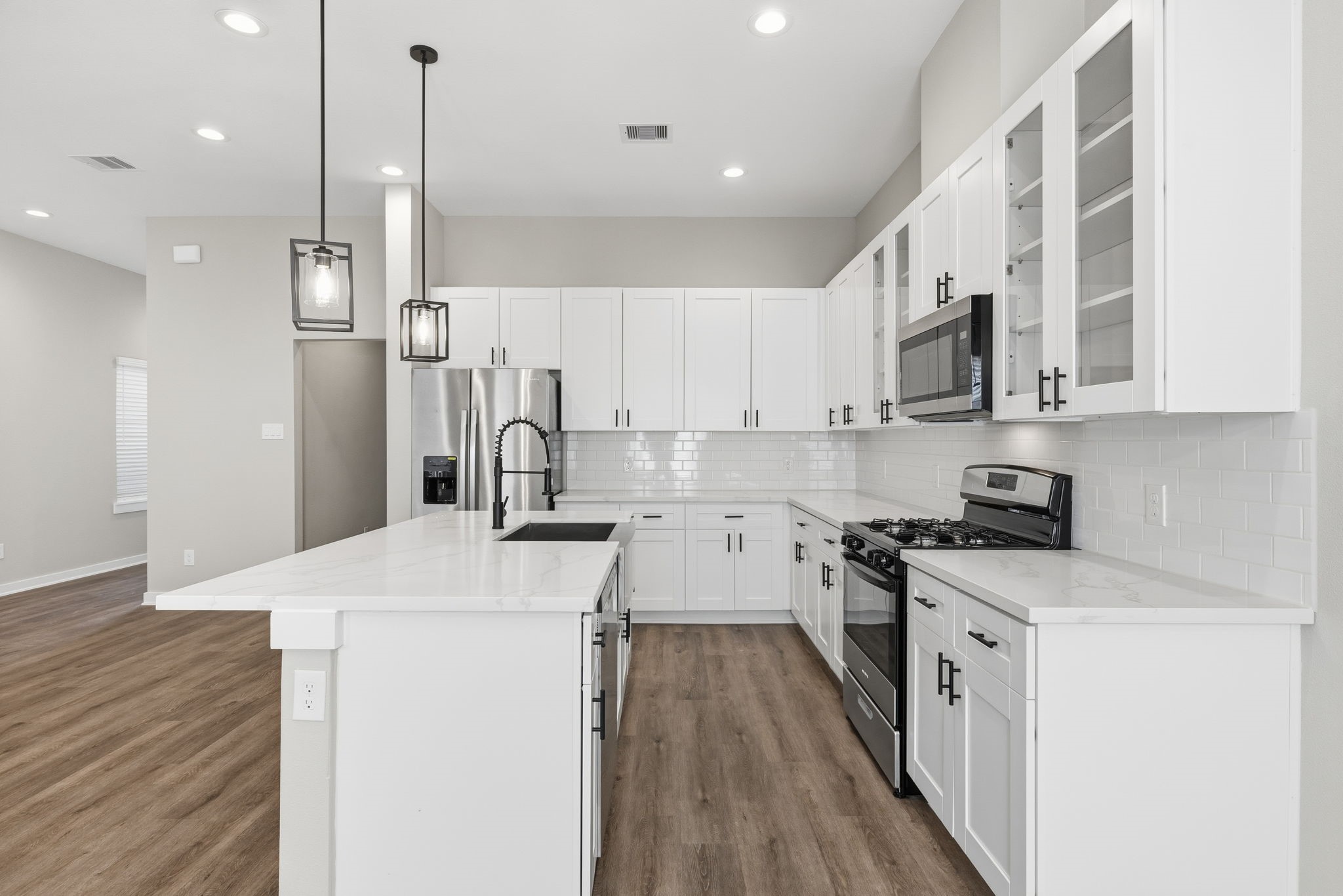 412 Stonework Landing Lane Houston, TX 77076 - Photo 9 of 30 a kitchen with stainless steel appliances a stove a sink a refrigerator and white cabinets with wooden floor