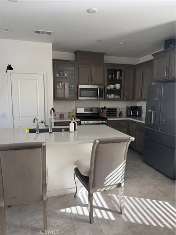 a kitchen with stainless steel appliances granite countertop a sink a stove a refrigerator cabinets and chairs