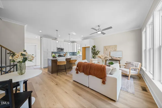 a living room with furniture kitchen view and a large window