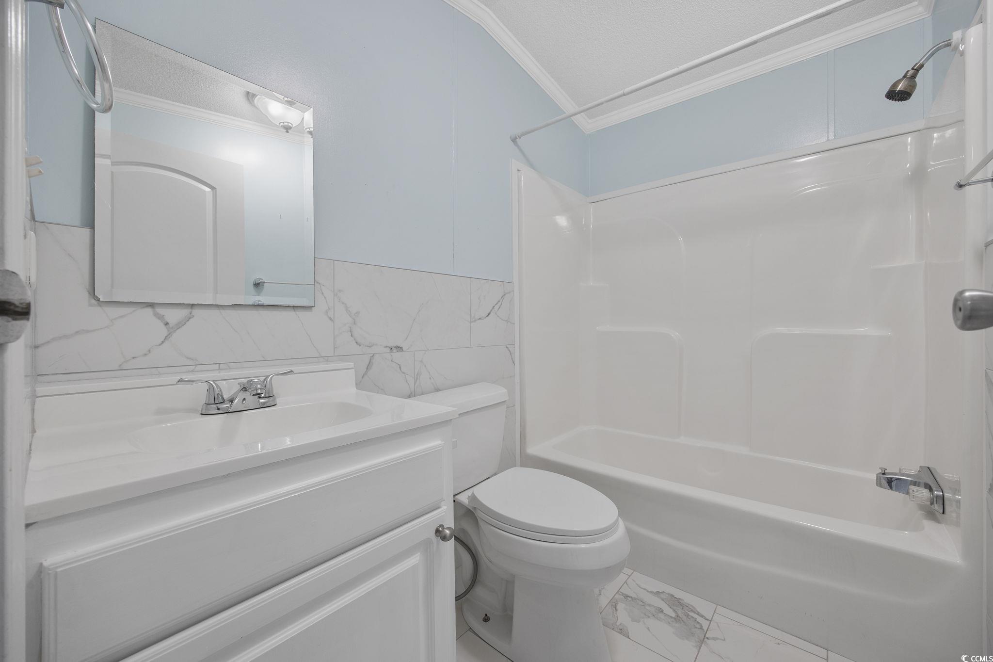 2000 Highway 15 Myrtle Beach, SC 29577 - Photo 15 of 27 Full bathroom featuring ornamental molding, shower / bathtub combination, vanity, tile walls, and marble finish floors