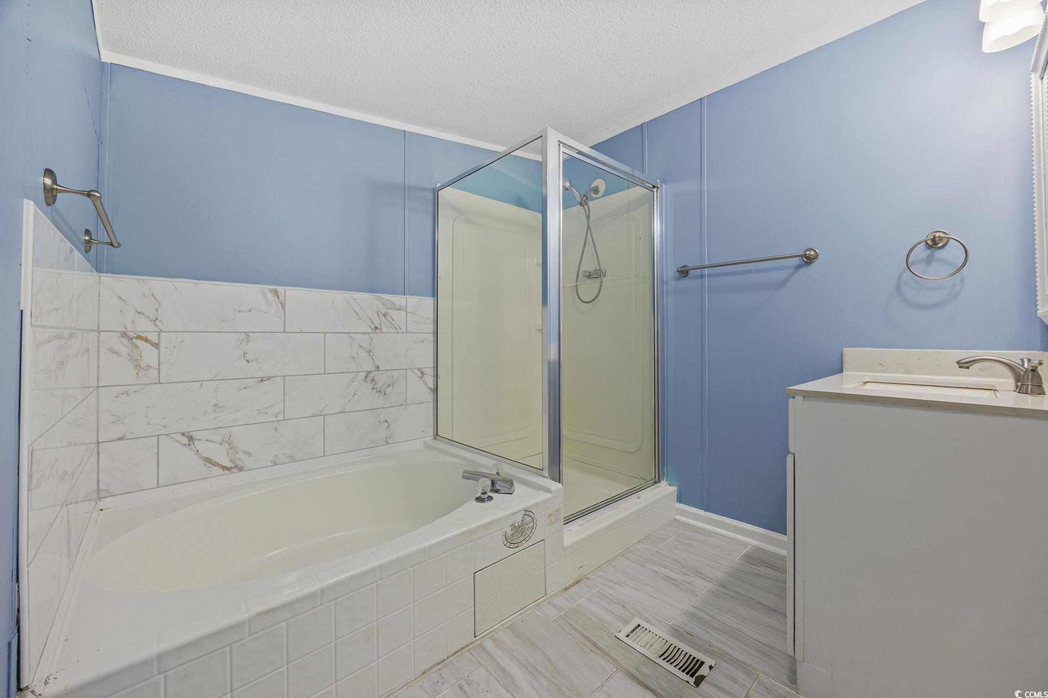 2000 Highway 15 Myrtle Beach, SC 29577 - Photo 16 of 27 Full bath featuring vanity, a shower stall, a garden tub, and a textured ceiling