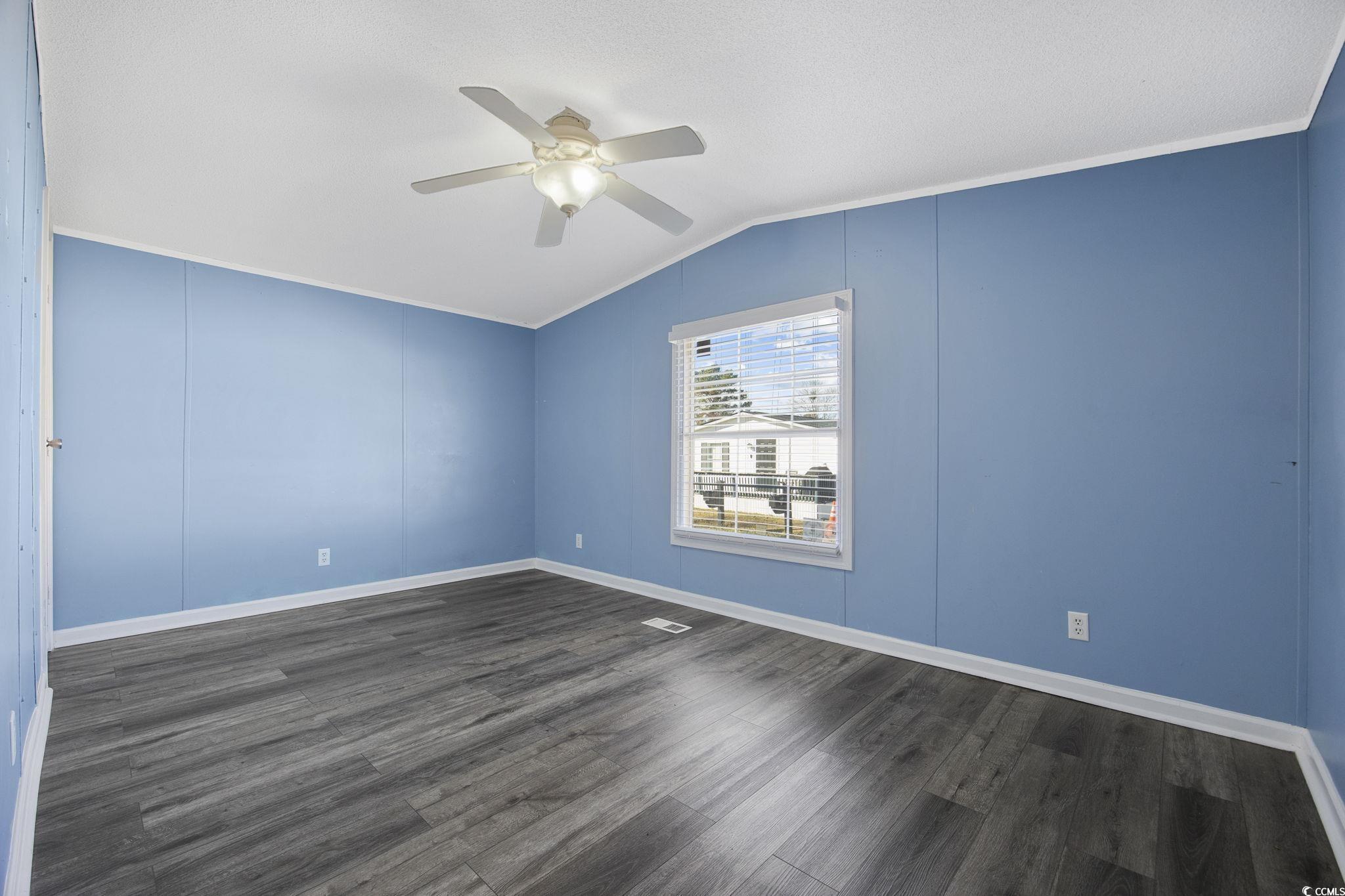 2000 Highway 15 Myrtle Beach, SC 29577 - Photo 18 of 27 Unfurnished room with dark wood-style floors, vaulted ceiling, a ceiling fan, and a decorative wall