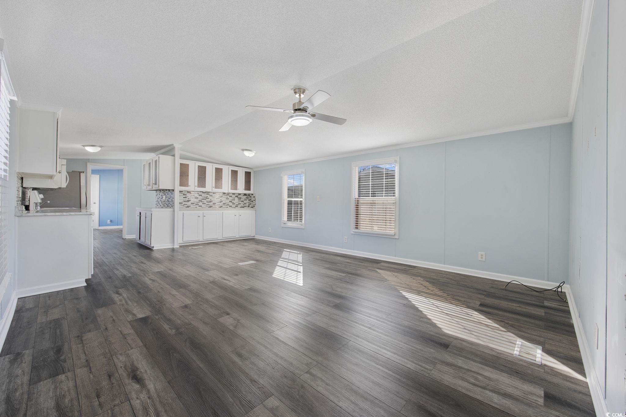 2000 Highway 15 Myrtle Beach, SC 29577 - Photo 3 of 27 Unfurnished living room featuring lofted ceiling, dark wood-style flooring, ceiling fan, and crown molding