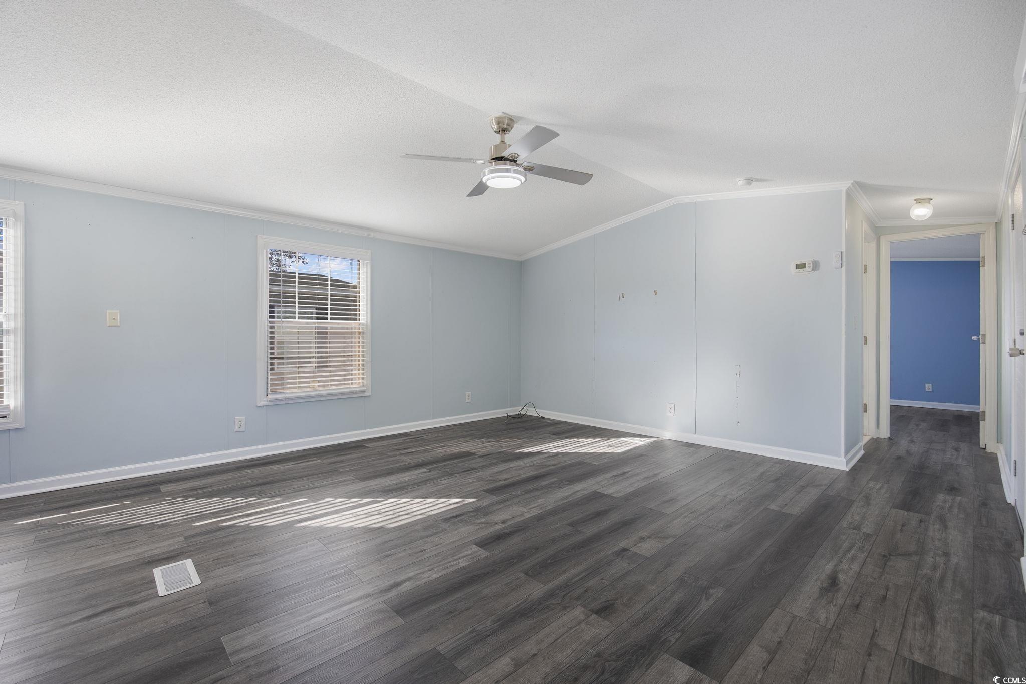 2000 Highway 15 Myrtle Beach, SC 29577 - Photo 5 of 27 Empty room with ornamental molding, dark wood finished floors, vaulted ceiling, and a ceiling fan