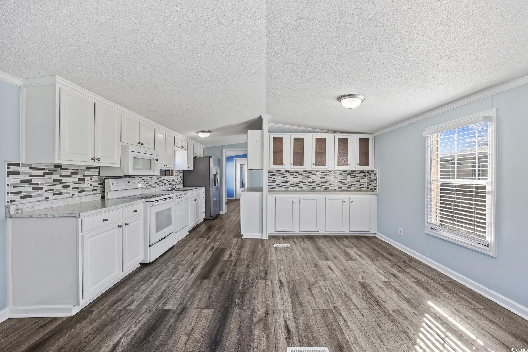 2000 Highway 15 Myrtle Beach, SC 29577 - Photo 7 of 27 Kitchen featuring white cabinetry, vaulted ceiling, white appliances, decorative backsplash, and a textured ceiling