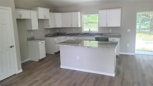 a kitchen with stainless steel appliances granite countertop a stove a sink and white cabinets with wooden floor