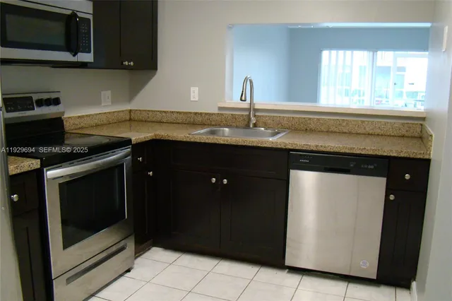 a kitchen with granite countertop a stove sink and microwave