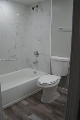 a white toilet sitting next to a bath tub and a shower