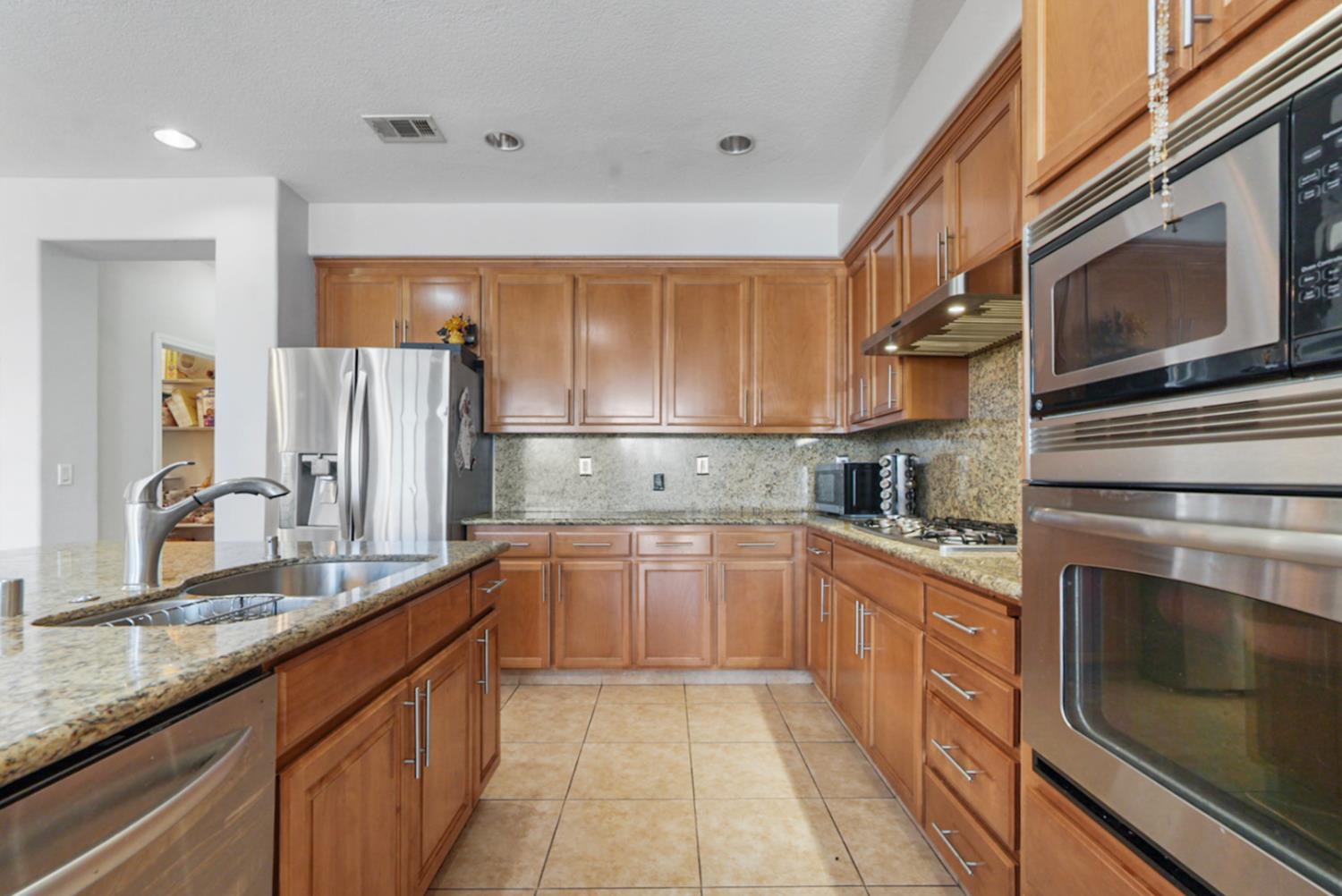 16501 Upper Pasture Lathrop, CA 95330 - Photo 13 of 41 a kitchen with stainless steel appliances granite countertop a refrigerator and a stove top oven