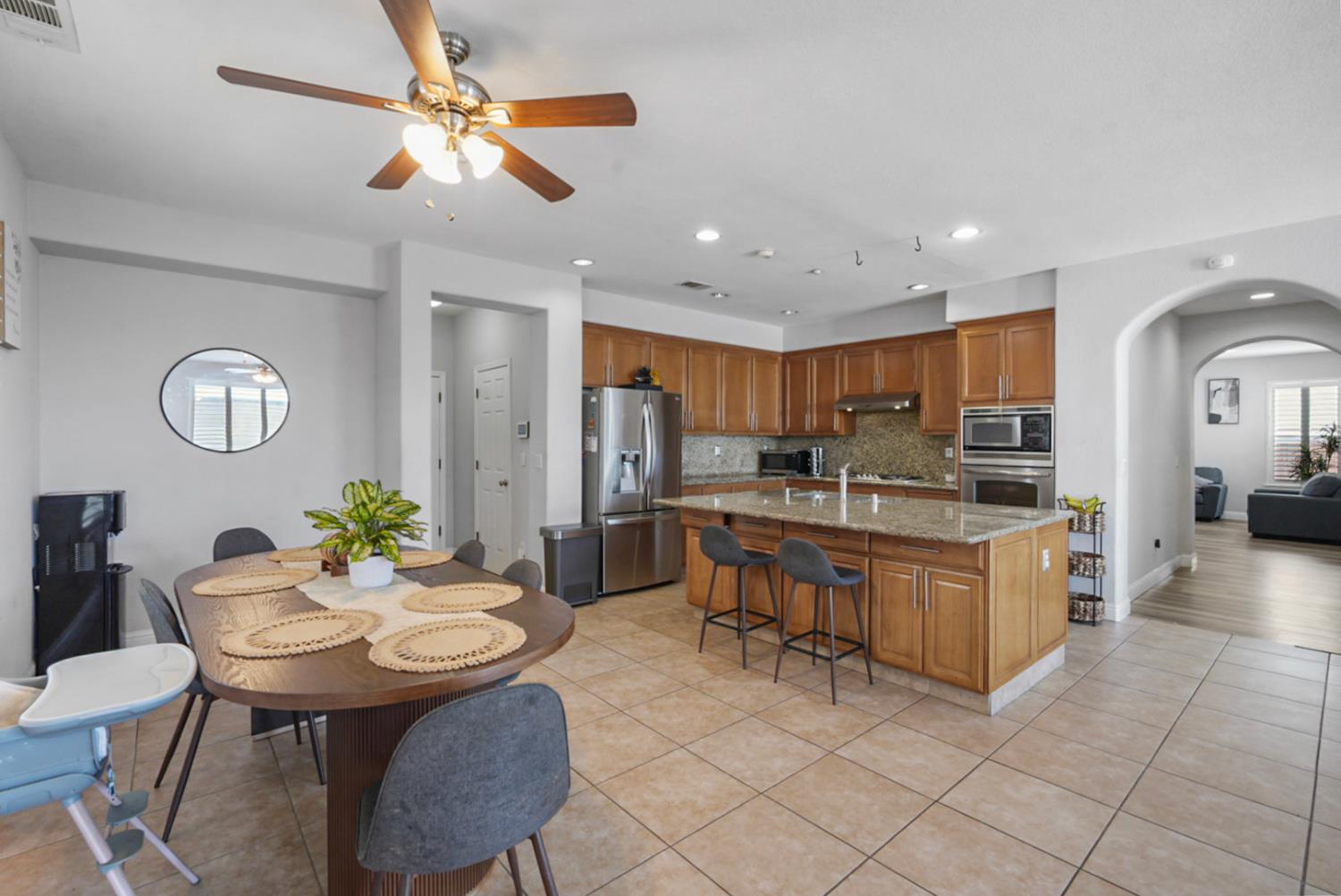 16501 Upper Pasture Lathrop, CA 95330 - Photo 15 of 41 a kitchen with stainless steel appliances kitchen island granite countertop a sink a stove a dining table and chairs