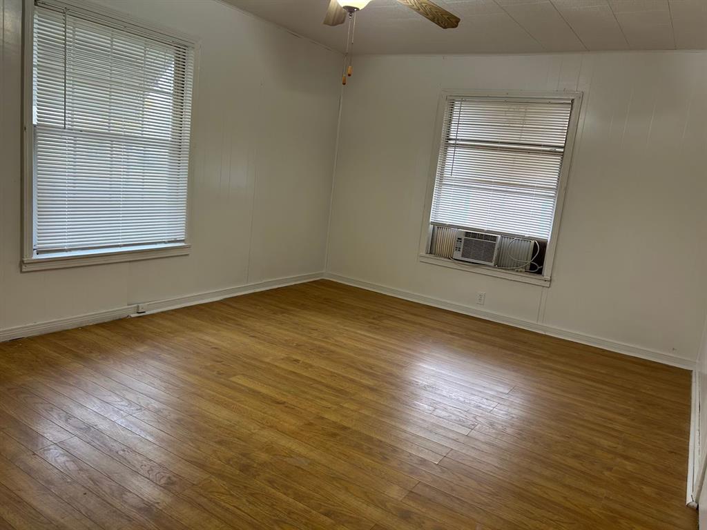 1411 James Street Sweetwater, TX 79556 - Photo 3 of 10 an empty room with wooden floor cabinet and windows