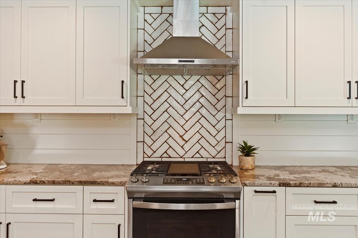 13712 Jarett Street Caldwell, ID 83607 - Photo 16 of 39 Kitchen featuring stainless steel gas range oven, white cabinets, wall chimney exhaust hood, and light stone countertops