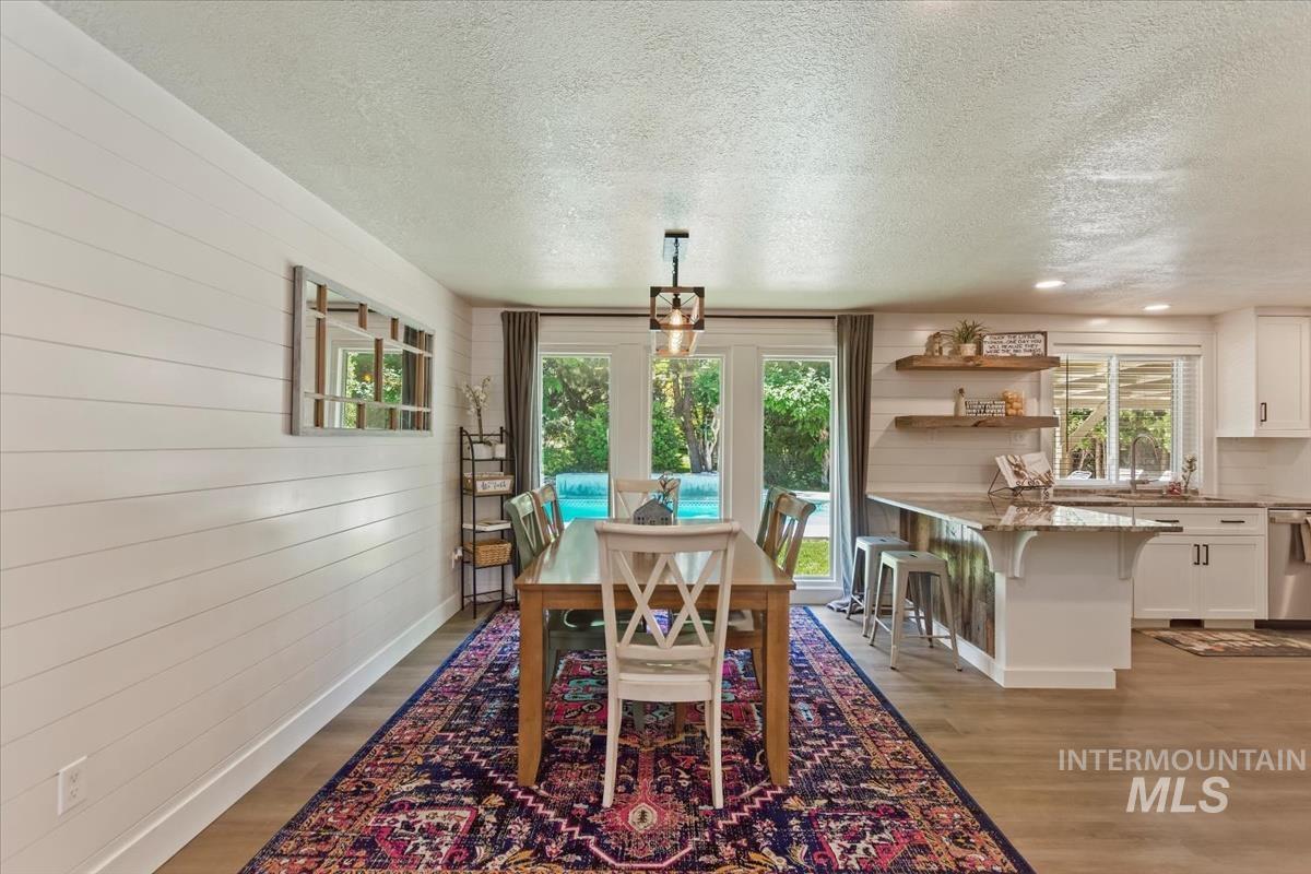 13712 Jarett Street Caldwell, ID 83607 - Photo 7 of 39 Dining space featuring a textured ceiling, light wood-style flooring, wooden walls, and plenty of natural light