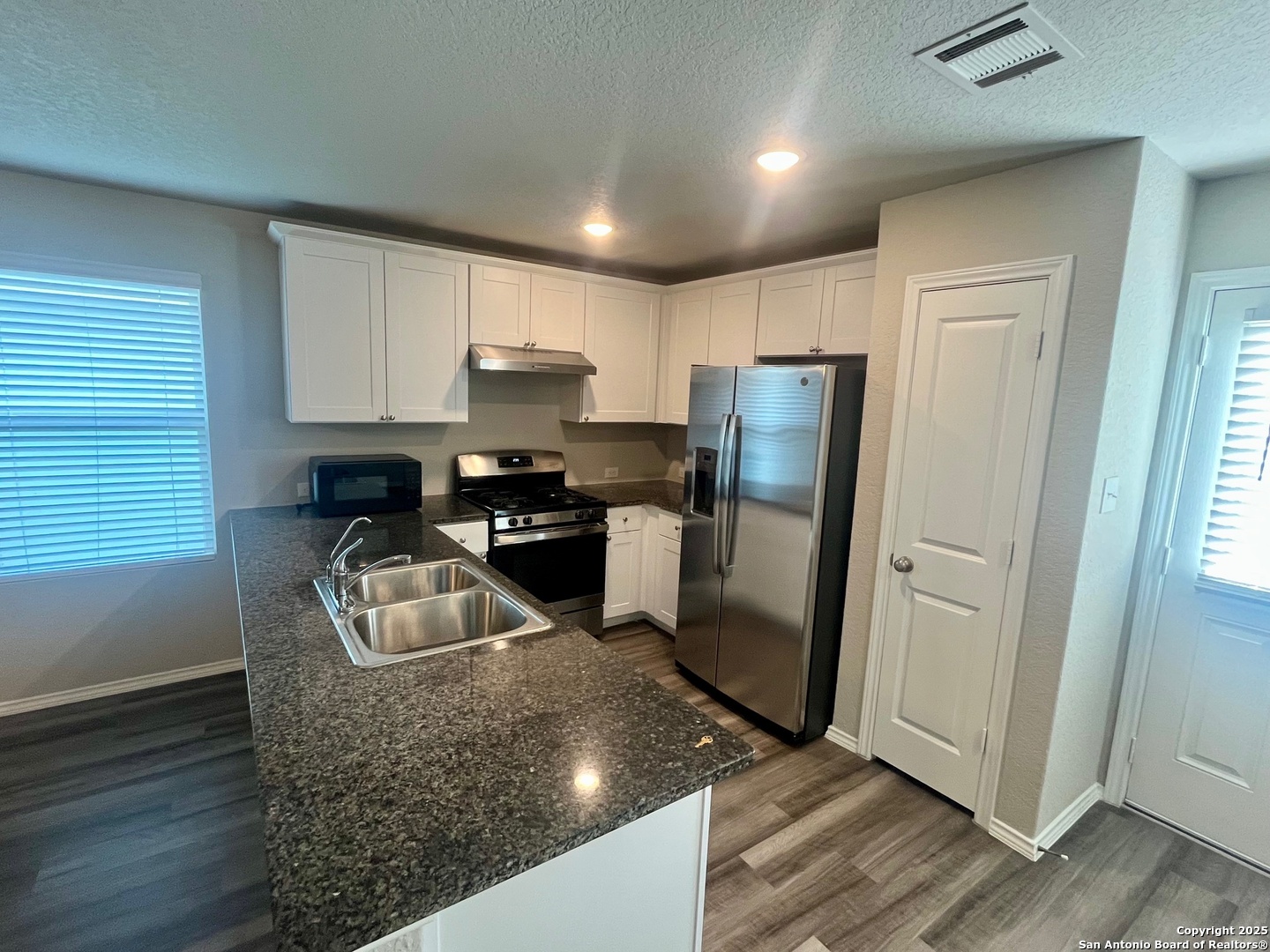 10418 Midsummer Meadow Converse, TX 78109 - Photo 10 of 24 a kitchen with stainless steel appliances granite countertop a refrigerator a stove a sink a washer dryer and white cabinets