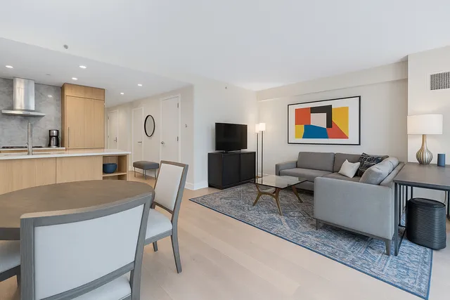 a living room with furniture a flat screen tv and kitchen view