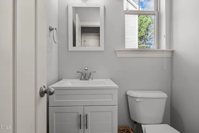 a bathroom with a toilet sink vanity and mirror