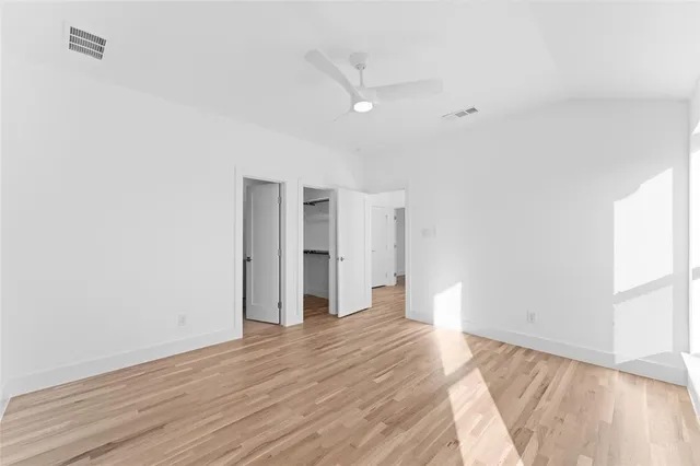 a view of empty room with wooden floor and fan