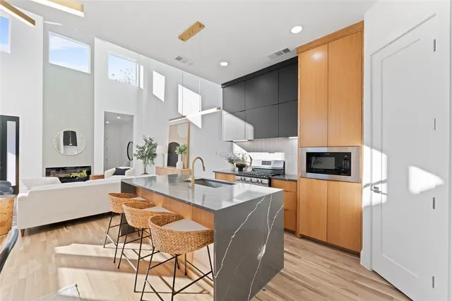 a living room with stainless steel appliances furniture a rug and a kitchen view