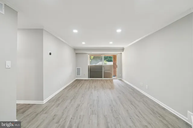 a view of an empty room with wooden floor and entryway