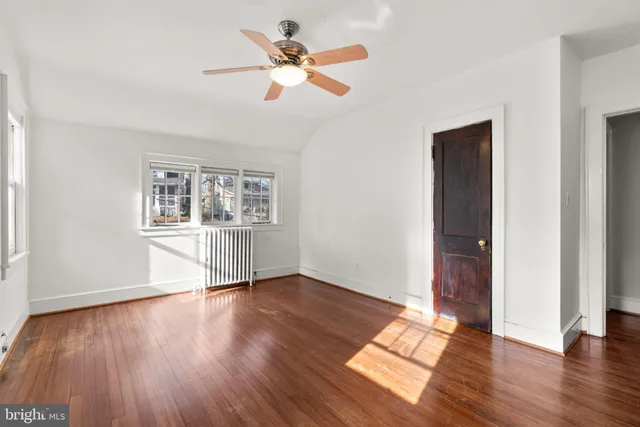 an empty room with wooden floor chandelier fan and windows