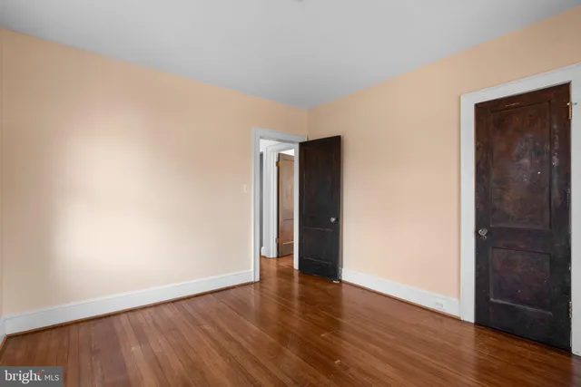 a view of an empty room with wooden floor and closet