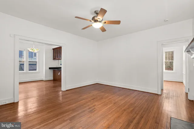 a view of an empty room with window and wooden floor