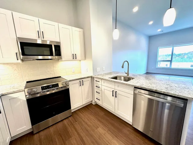 a kitchen with granite countertop white cabinets and stainless steel appliances
