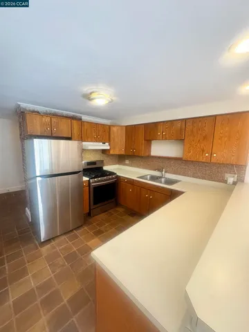 a kitchen with stainless steel appliances granite countertop a refrigerator a sink a stove and white cabinets