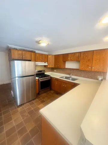 a kitchen with stainless steel appliances granite countertop a refrigerator a sink a stove and island