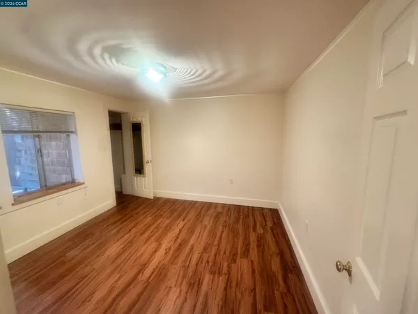 a view of an empty room with wooden floor and a window