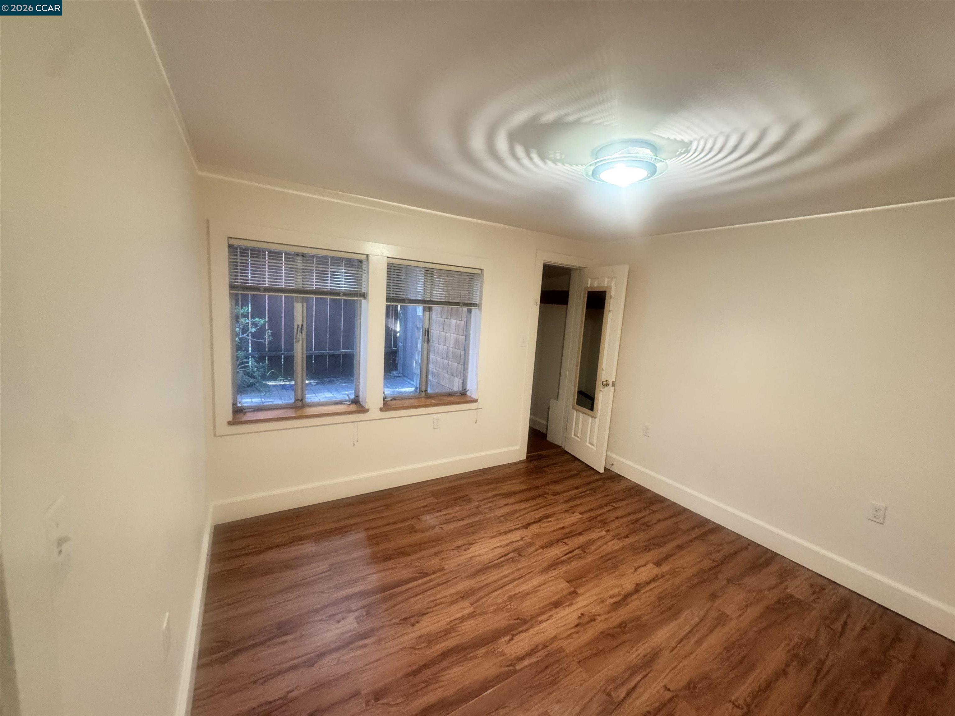 1723 Carleton Street, Unit A Berkeley, CA 94703 - Photo 21 of 32 a view of an empty room with wooden floor and a window