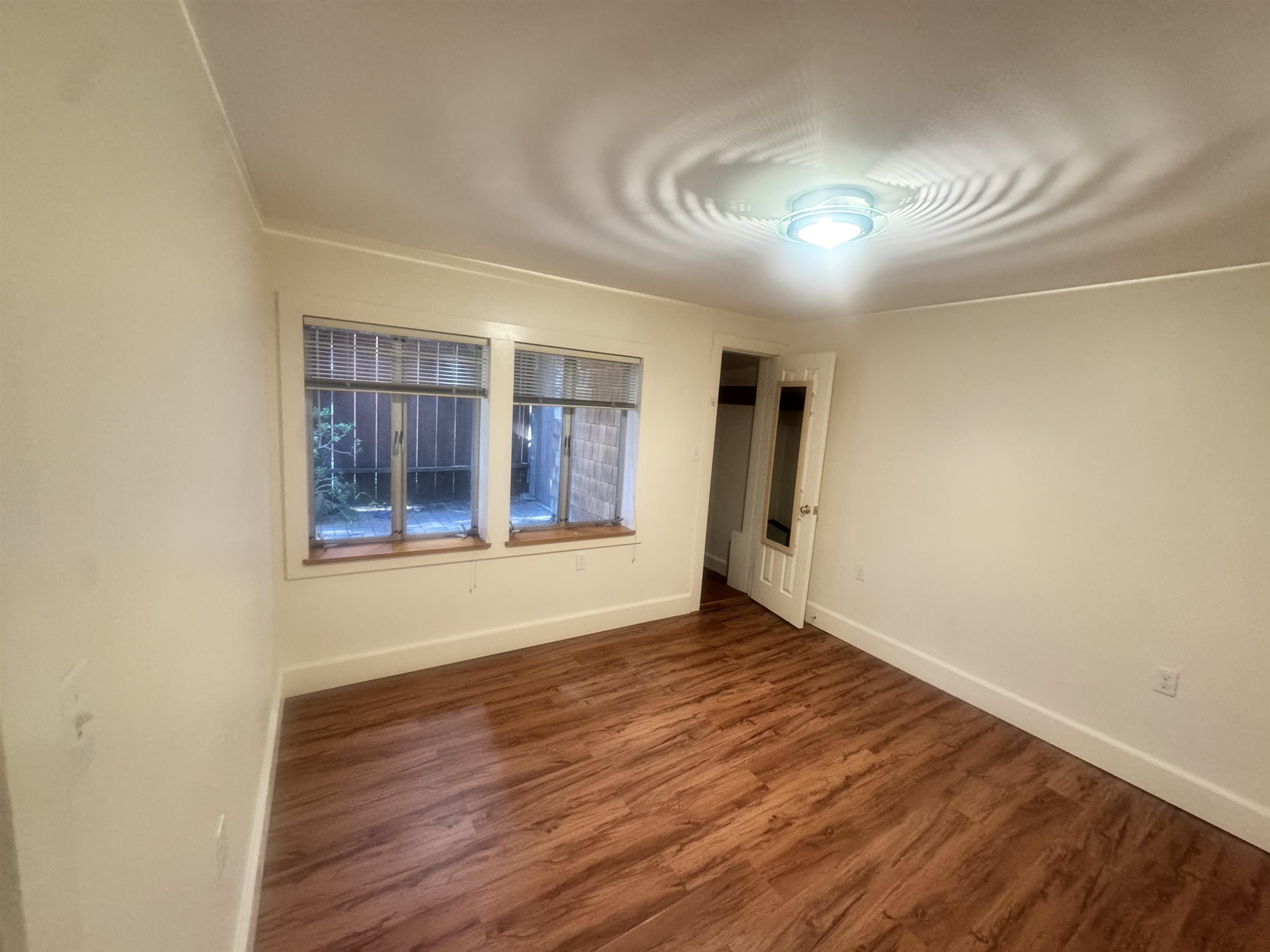 1723 Carleton Street, Unit A Berkeley, CA 94703 - Photo 21 of 32 a view of an empty room with wooden floor and a window